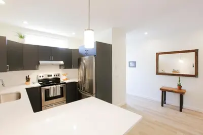 a kitchen with black and white cabinets and a refrigerator at Aurelia Guest Suite and Sauna in Tofino