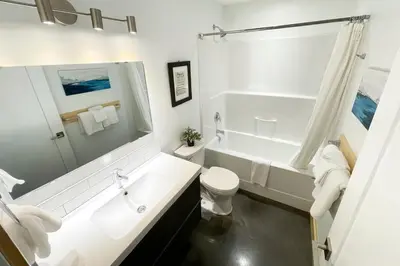 a white bathroom with a tub and a toilet at Tidal Retreat Cabin in Tofino