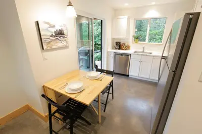 a kitchen with a table with chairs and a refrigerator at Tidal Retreat Cabin in Tofino