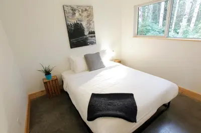 a bedroom with a white bed with a black blanket at Tidal Retreat Cabin in Tofino