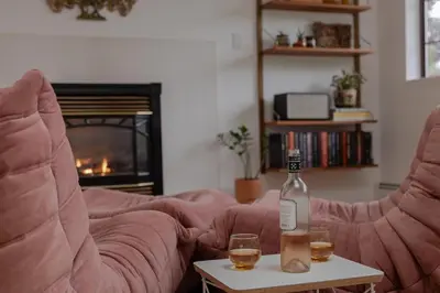 a bottle of wine and two glasses on a table in a living room at The Cougar Den in Tofino