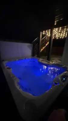 a bath tub filled with blue water at night at Cozy Garden Suite with Hot Tub and Perfectly Located in Goldstream Station