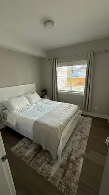 a bedroom with a large bed and a window at Cozy Garden Suite with Hot Tub and Perfectly Located in Goldstream Station