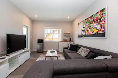 a living room with a couch and a flat screen tv at Cozy Garden Suite with Hot Tub and Perfectly Located in Goldstream Station