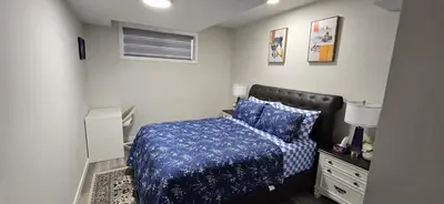 a bedroom with a bed with a blue comforter at Bleniel Place - Stylish Basement Suite with Wi-Fi Netflix & Parking in Edmonton