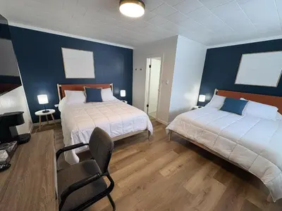 a bedroom with two beds and a chair in it at Remo Stays in Unity