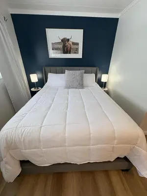 a bedroom with a large white bed with a bull on the wall at Remo Stays in Unity