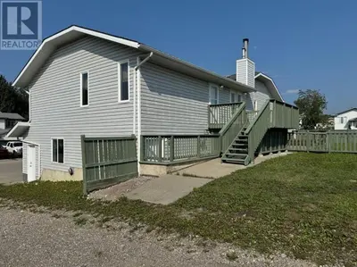 a gray house with a porch and a fence at Alpenglow Oasis in Hinton