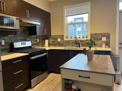 a kitchen with brown cabinets and a stove top oven at Sunlit Haven in Calgary