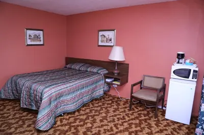 a hotel room with a bed and a chair at Timberlodge RV & Campground in Port Alberni