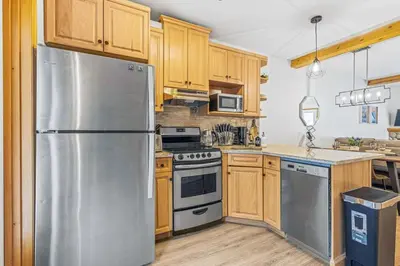 a kitchen with wooden cabinets and a stainless steel refrigerator at Scenic 2BR Haven with MTN Views Near DT Banff in Canmore