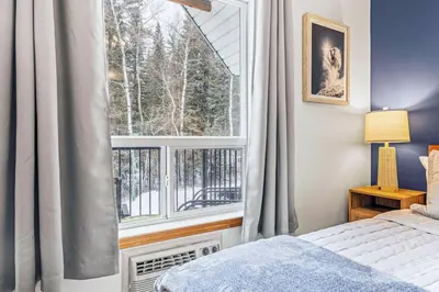 a bedroom with a bed and a large window at Scenic 2BR Haven with MTN Views Near DT Banff in Canmore
