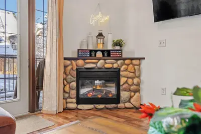 a stone fireplace in a living room with a fire place at 2BR Mystic Springs Escape with BBQ, Pool, Hot tub in Canmore