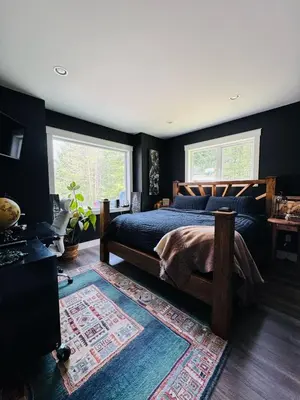 a bedroom with a bed and two windows at Shawnigan Lake Retreat with Theatre in Shawnigan Lake