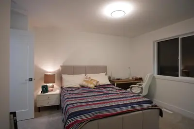 a bedroom with a bed and a desk and a window at Peaceful Coquitlam Escape, Modern New Home, Minutes to Transit in Coquitlam
