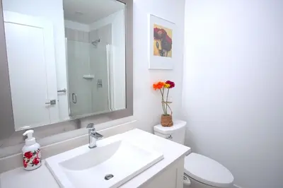 a white bathroom with a sink and a toilet at Peaceful Coquitlam Escape, Modern New Home, Minutes to Transit in Coquitlam