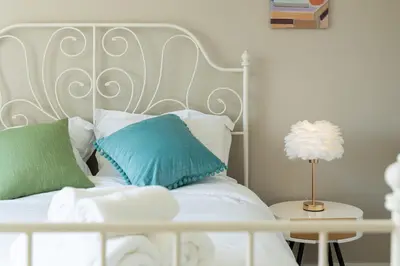 a white bed with green and white pillows and a table at Sunnymede Vacation Stay in Richmond