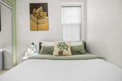a bedroom with a bed with white sheets and a window at Downtown Den - Steps Away from Worlds Largest Dino in Drumheller