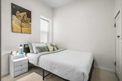 a white bedroom with a bed and a window at Downtown Den - Steps Away from Worlds Largest Dino in Drumheller