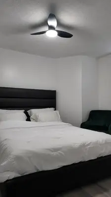 a bedroom with a white bed with a ceiling fan at 2bedroom, 2bed day light Suite in a nice and secured neighborhood in Prince George