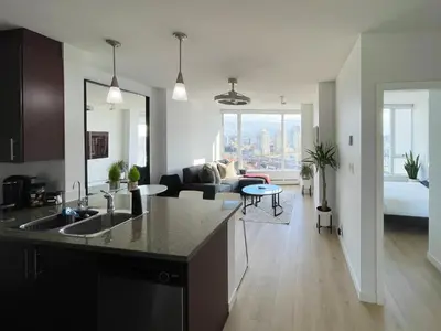 a kitchen and living room with a couch and a table at Condo Downtown Vancouver - Near Rogers Arena & BC Place w Parking in Vancouver