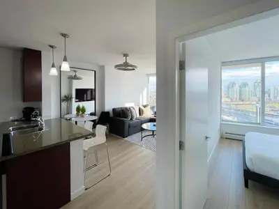 a kitchen and living room with a view of a city at Condo Downtown Vancouver - Near Rogers Arena & BC Place w Parking in Vancouver