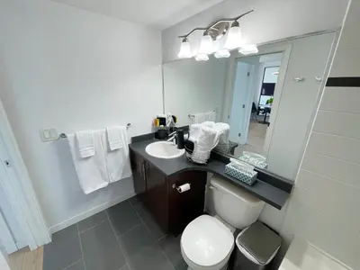 a bathroom with a sink and a toilet and a mirror at Condo Downtown Vancouver - Near Rogers Arena & BC Place w Parking in Vancouver