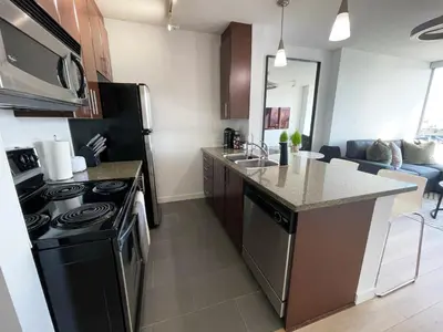 a kitchen with a black refrigerator and a stove at Condo Downtown Vancouver - Near Rogers Arena & BC Place w Parking in Vancouver