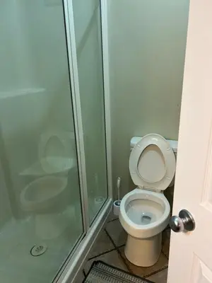 a bathroom with a toilet and a glass shower at Unique home services in Bélanger