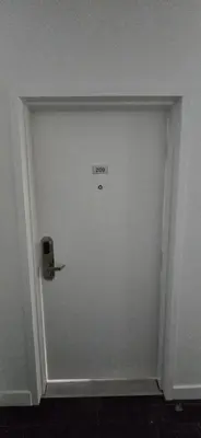 a white door with a sign on it in a room at New Royal Inn in New Westminster