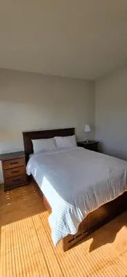 a bedroom with a large white bed and a nightstand at New Royal Inn in New Westminster