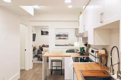 a kitchen and living room with white cabinets and a table at Little Nest in Calgary