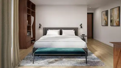 a bedroom with a large bed with a green bench at The Como Hotel in Vancouver