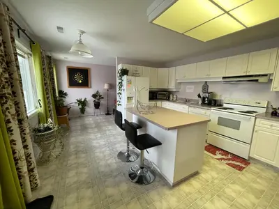 a kitchen with white cabinets and a counter and stools at Imperial Ranchettes GuestSuite in Lone Butte