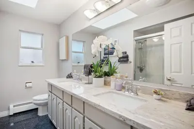 a white bathroom with a sink and a toilet at 6 Bedroom Family Home with Indoor Arcade, BBQ, Huge Backyard & Pickleball in Vancouver