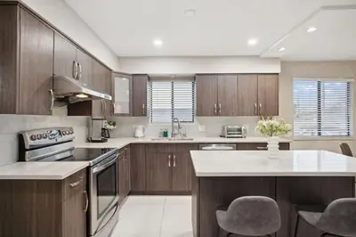 a kitchen with wooden cabinets and a counter top at 6 Bedroom Family Home with Indoor Arcade, BBQ, Huge Backyard & Pickleball in Vancouver