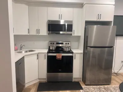 a kitchen with white cabinets and a stainless steel refrigerator at Home sweet home in Calgary