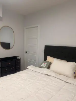 a bedroom with a white bed with a black headboard and a mirror at Home sweet home in Calgary