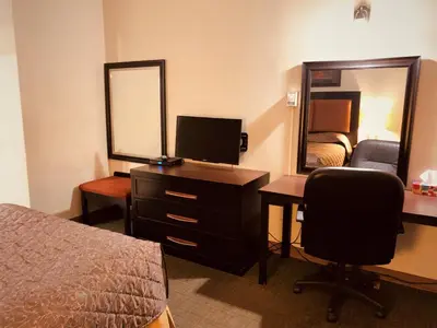 a hotel room with a bed and a desk and a mirror at Red Carpet Inn & Suites in Calgary