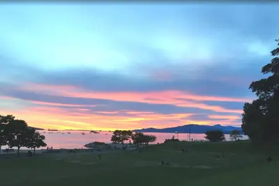 a sunset over a field with a body of water at Luxury Downtown Vancouver Home Near Sunset Beach with Parking in Vancouver