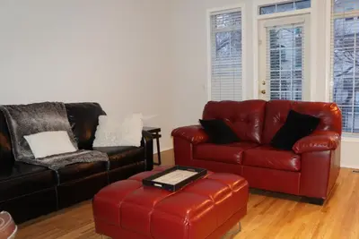 a living room with two chairs and a red leather couch at Discover Tranquility in this 2 bed townhouse in Vancouver