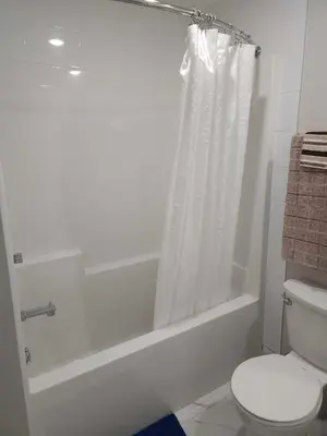 a bathroom with a toilet and a bathtub with a shower curtain at Discover Tranquility in this 2 bed townhouse in Vancouver