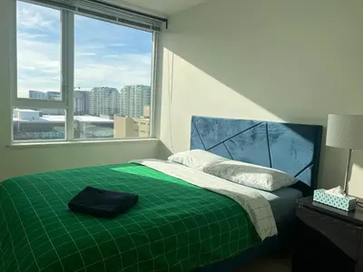 a bedroom with a green bed with a large window at Elegant &comfortable room1B &1B apartment perfect location in Richmond