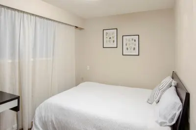 a white bedroom with a bed and a window at Close to YVR! Convenient 3BR Stay for Every Occasion in Vancouver