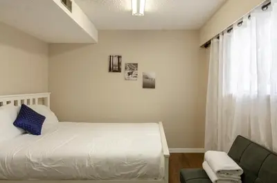 a bedroom with a bed and a couch and a window at Close to YVR! Convenient 3BR Stay for Every Occasion in Vancouver