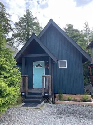 a blue house with a blue door and stairs at Tide and Trail- Cabin in Ucluelet in Ucluelet