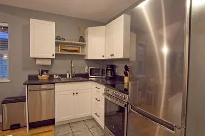 a kitchen with white cabinets and a stainless steel refrigerator at Tide and Trail- Cabin in Ucluelet in Ucluelet