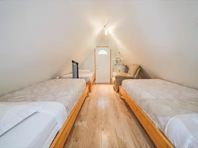 a attic bedroom with two beds and a flat screen tv at Surf Haven - Cabin in Ucluelet - Sleeps 5 in Ucluelet