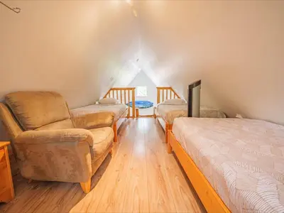 a attic room with a bed and a chair and a couch at Surf Haven - Cabin in Ucluelet - Sleeps 5 in Ucluelet
