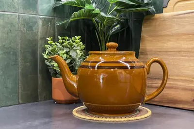 a brown tea pot sitting on a table with plants at Raven Lady #201- Ucluelet Sleeps 6 Pet Friendly in Ucluelet